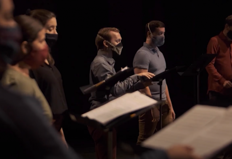 Choir members singing through facemasks on the Northrop stage