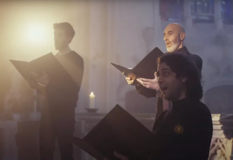 Three male singers hold choral folders in a chapel. Link to Kali Malone “All Life Long” (for voice) video - YouTube