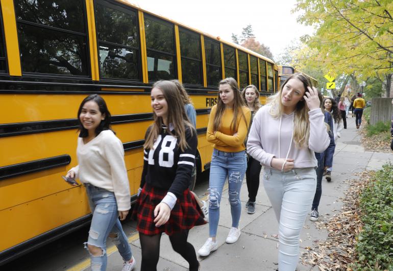 students in line for a bus smiling