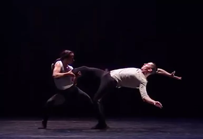 3. One dance holds the leg of another as he stretches backward