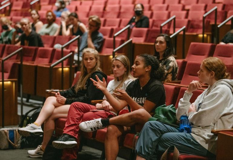 Students sitting in the Northrop theatre engaged in a discussion with people on the stage, who are not shown.