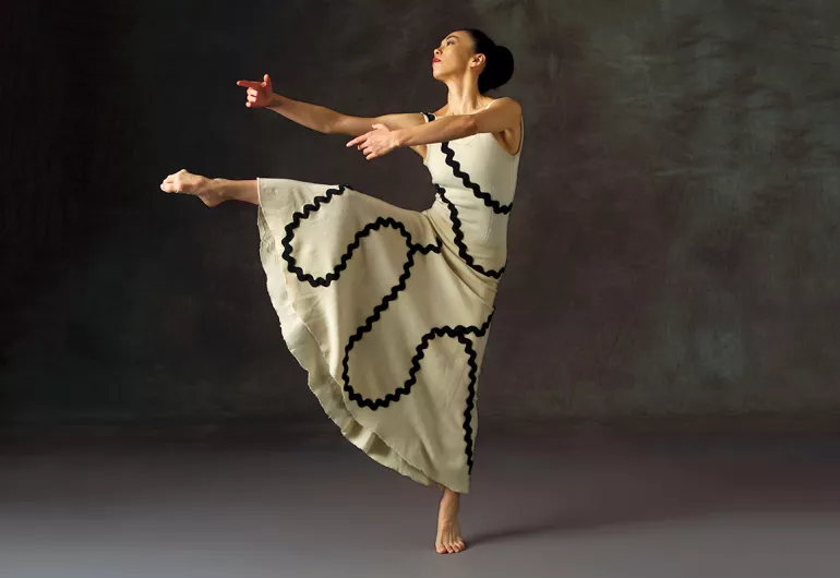 Martha Graham dancer in a dress with black ribbon design on a white.