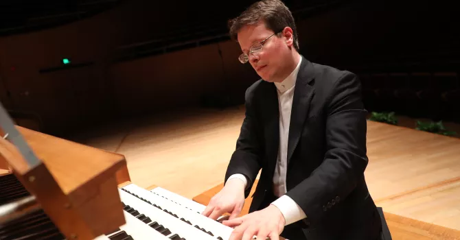 A male sits and plays an organ.