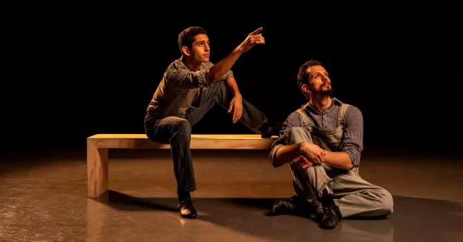 Two men from Of Mice and Men on stage. One is on a bench. One is on the floor.