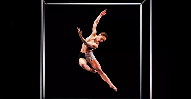 A single dancer in the air with arms upwards