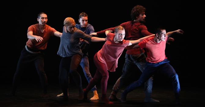 Modern dancers wearing red and blue in a circle