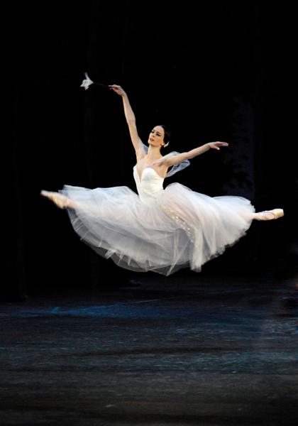Lead dancer in long white tutu leaps high above the stage