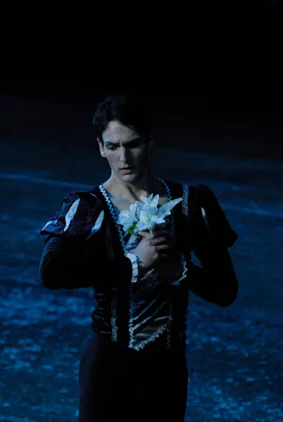 Male dancer holds flower to his chest, eyes cast down to the side