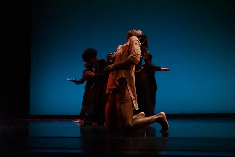 Dancers perform on stage against a dark blue backdrop.