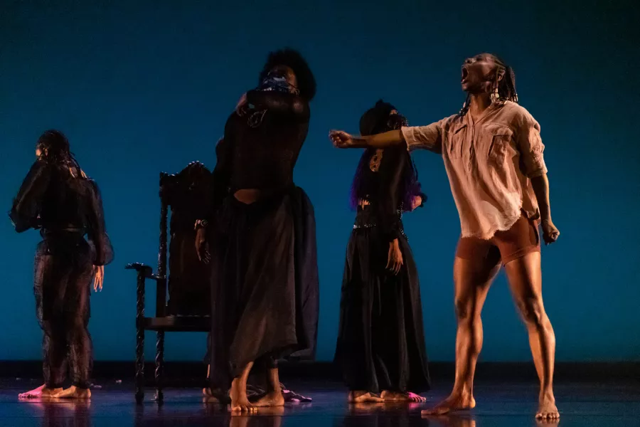 Dancers perform on stage against a dark blue backdrop.