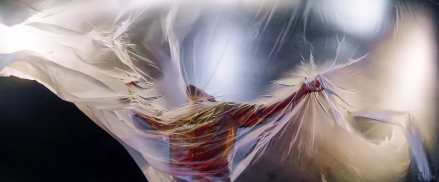 A dancer leans into a large plastic sheet.