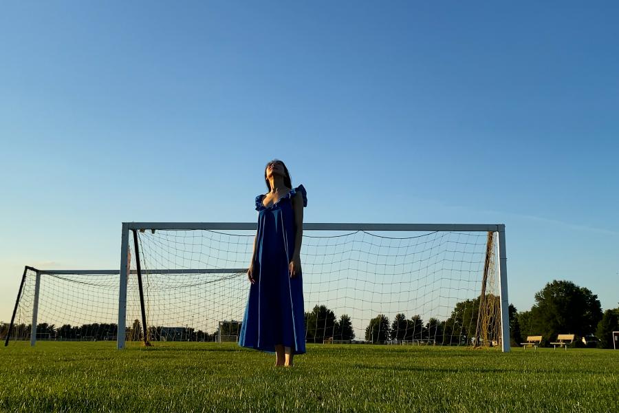 A person stands in a soccer field at dusk.