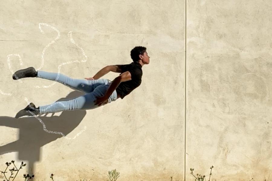 A person floats mid air against a concrete wall