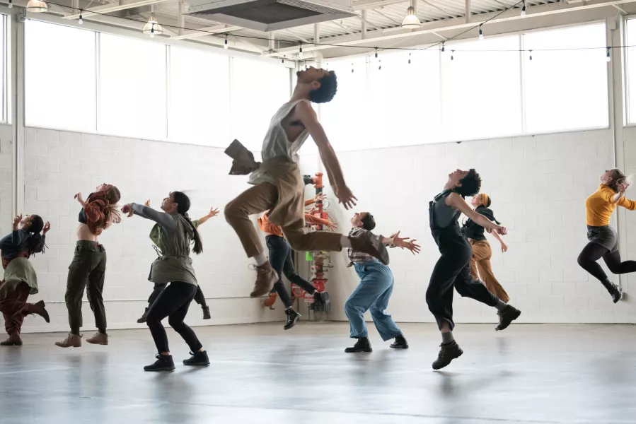 Film still - dancers in the studio - one jumping in a running pose high in the air