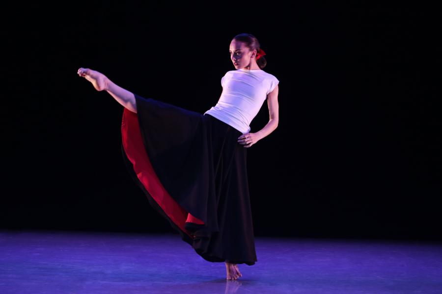 A dancer kicks up her leg and points her toes to the sky.
