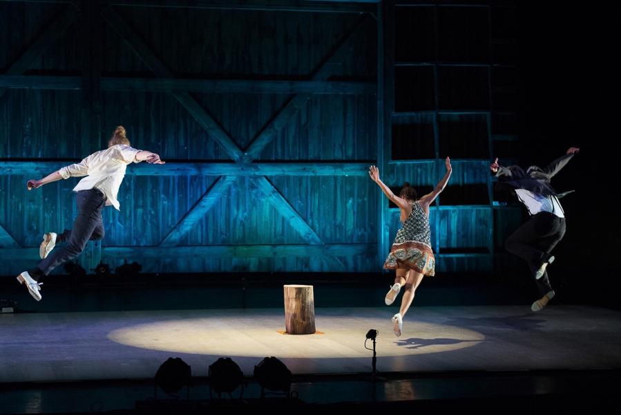 Three dancers jump in the air mid performance.