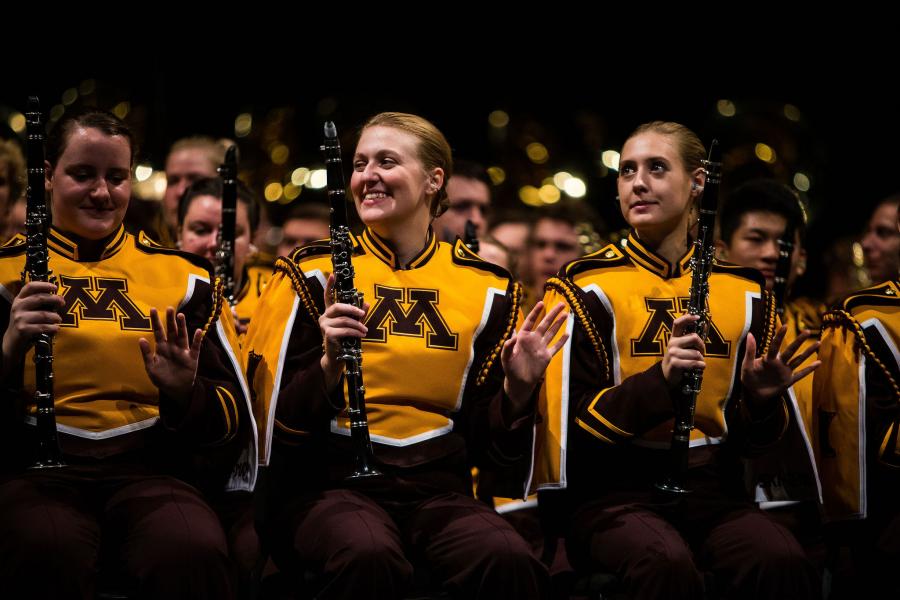 students in marching band uniforms smiling while holding instruments