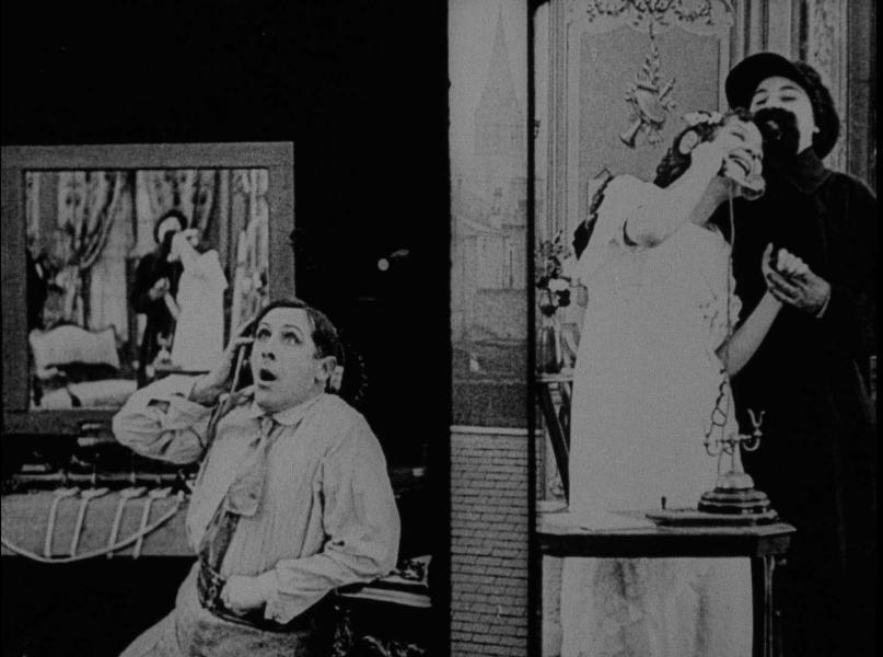 A black and white image is split down the middle. On the left shows a character on the telephone with a surprised expression on their face. On the right, shows two characters enclasped, while one holds the phone up to their ear with a smile. 