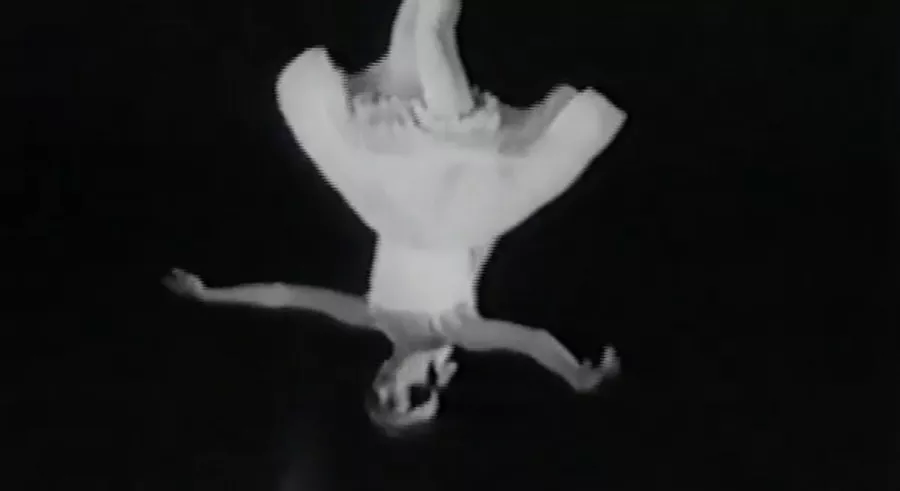 A black and white image that appears upside down shows a dancer twirling in motion, wearing a dress and ballet shoes.