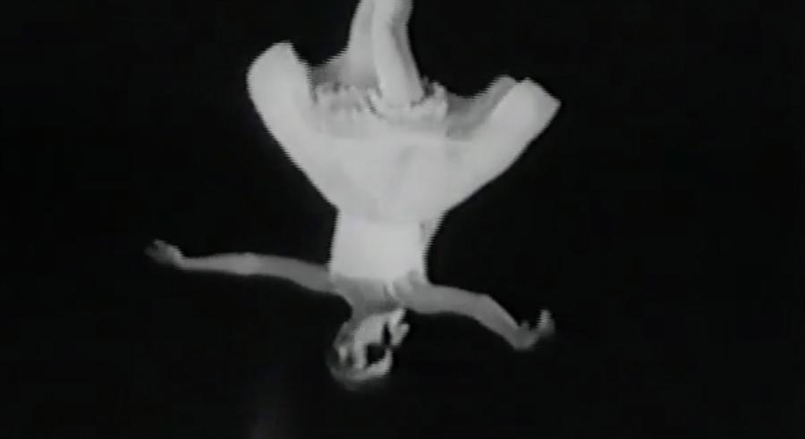 A black and white image that appears upside down shows a dancer twirling in motion, wearing a dress and ballet shoes.