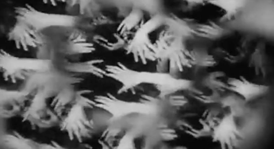 A black and white image shows multiple hands reaching toward one another in various directions, some in focus and others blurred.