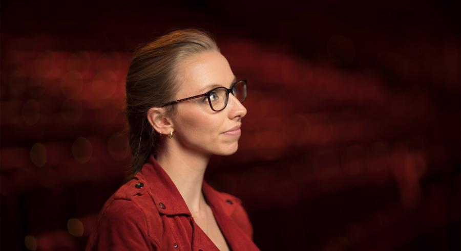 A side profile portrait shows a person with blond hair, glasses, and a red jacket looking off into the distance.