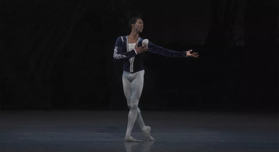 Male lead poses with one hand to heart and the other are open.