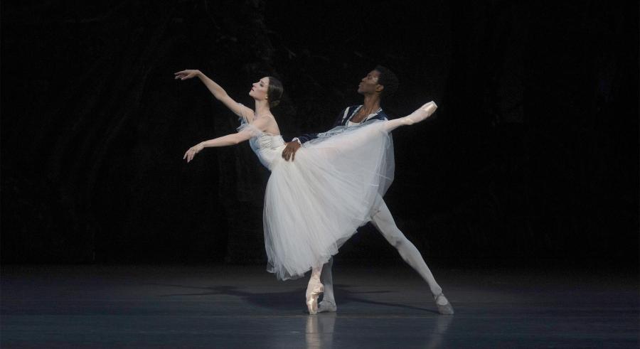 A male dancer supports a female dancer on pointe.