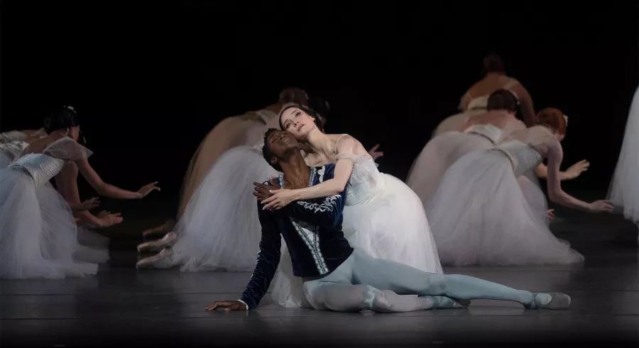 Two dancers embrace on the stage floor.