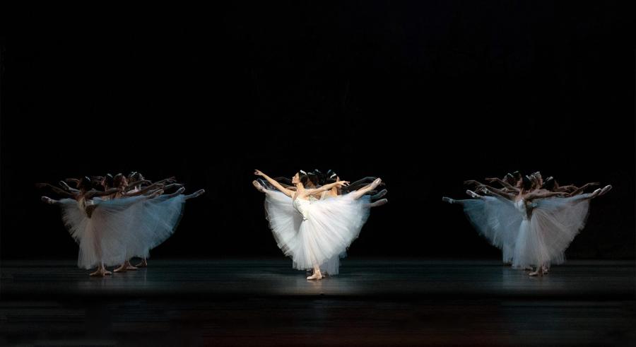 Three synchronized clusters of dancers strike the same pose at once.