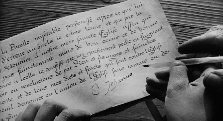 Black and white film still of a handwritten note in a non-English language.