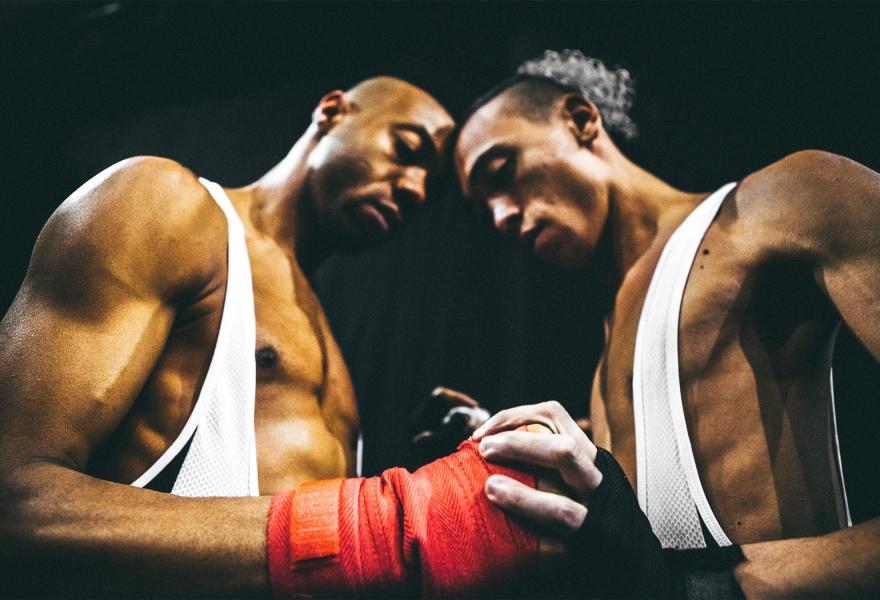 Two boxers join hands and press their heads together.