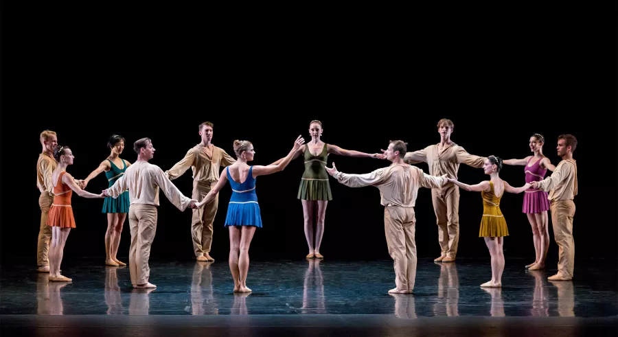 Dancers join hands in a wide circle.