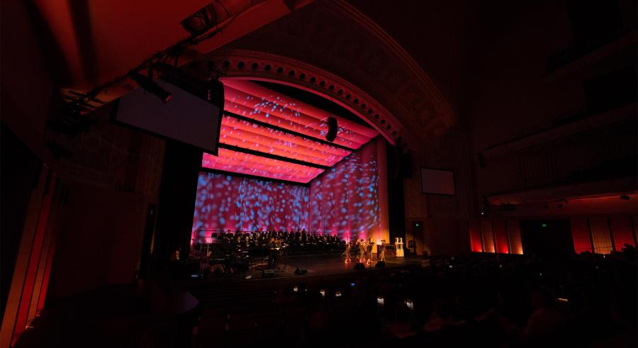The Carlson Family Stage emits a red glow in the dark theater.
