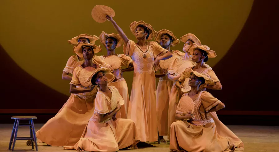Group of dancers wear period costumes onstage. 