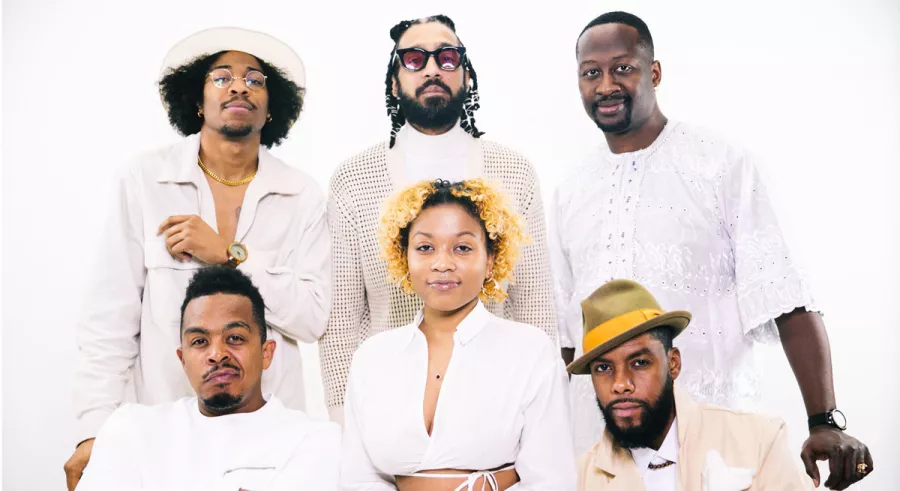 Members of The Poetic Diaspora in all white posing in front of a white background.