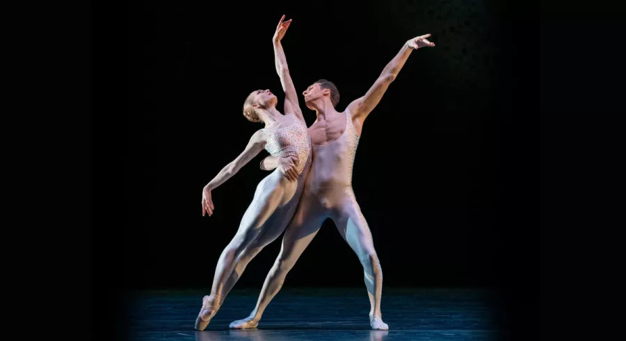 Dancer supports another dancer's weight as they lean on them. 