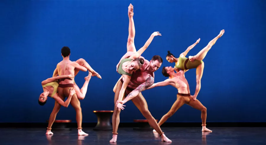 Dancers onstage performing tricks in which one dancer holds up another dancer in various poses.