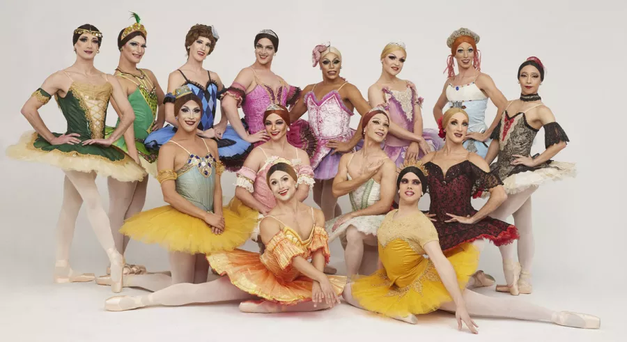 The dancers of Les Ballets Trockadero de Monte Carlo in various drag outfits posing in front of a white background.