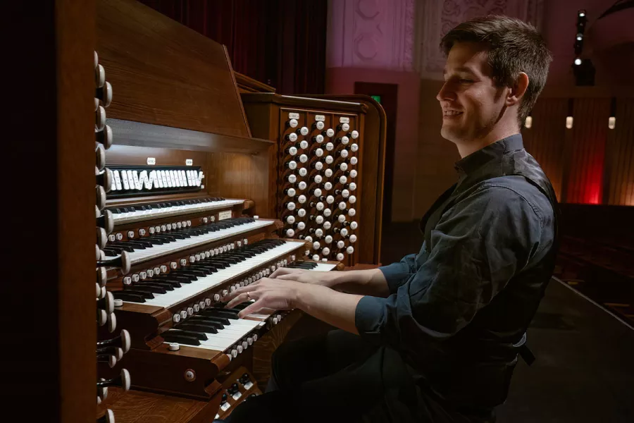Greg Zelek, a man with short brown hair in a navy button-up, plays the pipe organ.