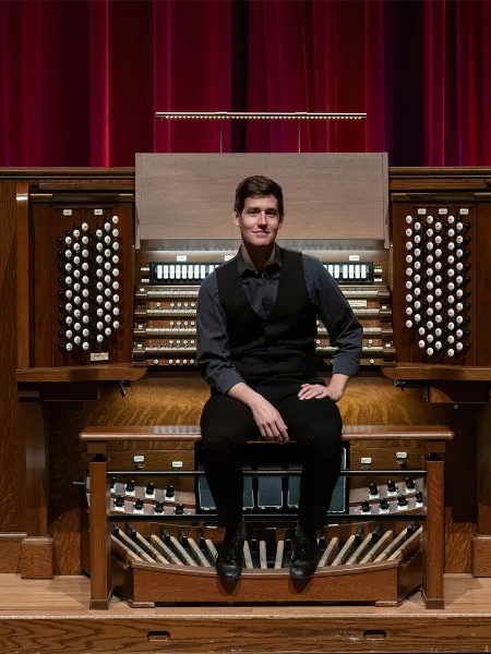 Greg sits on the Northrop organ bench facing the audience.