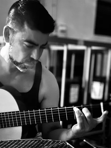 Black and white photo of Alvaro Bermudez playing his guitar.
