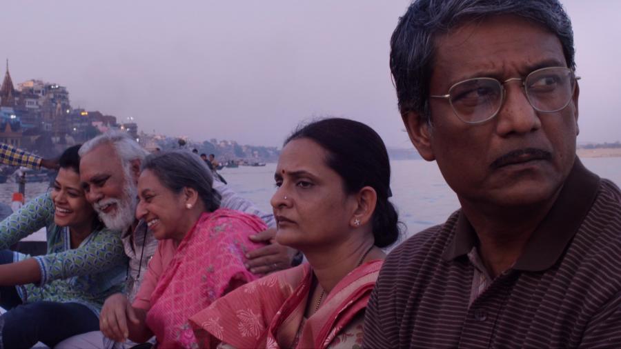 Four members of an Indian family sitting outside against a pink sunset