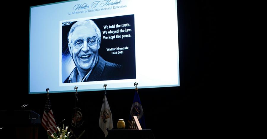 An image of Walter Mondale is on a white screen in front of a black background. The image reads “Walter F. Mondale. An Afternoon Remembrance and Reflection.” Next to the picture of Mondale the image reads “We told the truth. We obeyed the law. We kept the peace. Walter Mondale 1928-2021.”