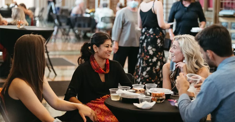 Photos of people sitting at a table eating and drinking. The subject of the photo is wearing a red skirt and black shirt. 