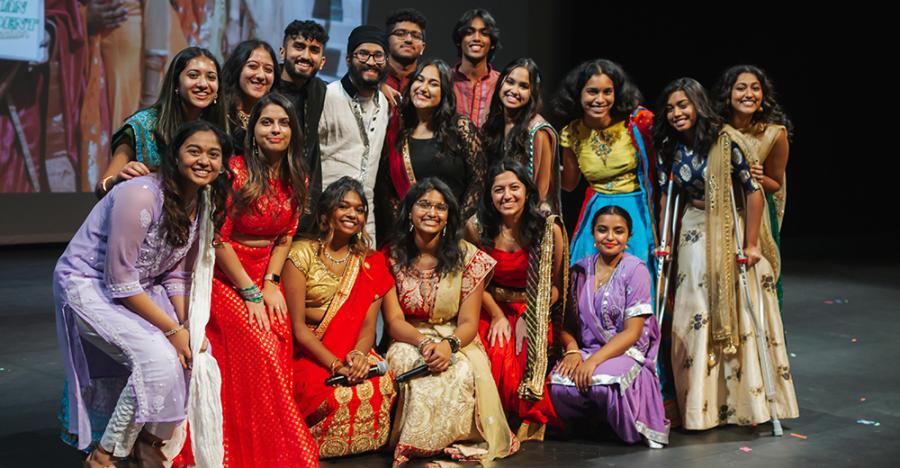 Photograph of the Indian Student Association in traditional costumes on stage for their Fall show.