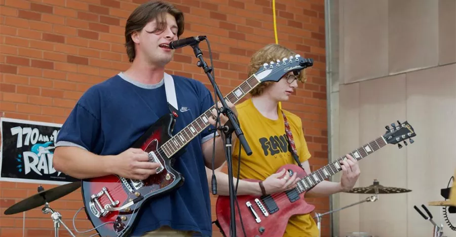 Students performing for Welcome Week and Radio K. Both students are playing the guitar, but one is also singing. 
