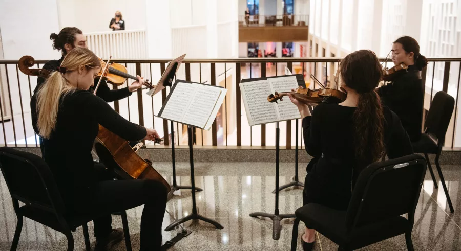Four seated lobby musicians play string instruments.