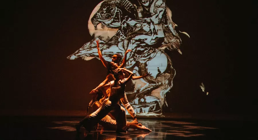 Four dancers overlap with one another as they strike poses with arms and legs extended in different directions.