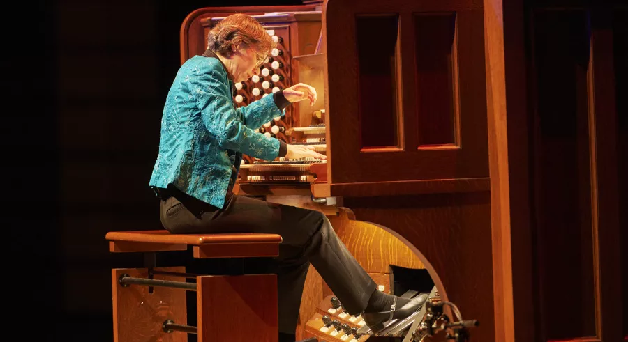 Isabelle Demers, wearing a bright blue jacket, plays the organ.